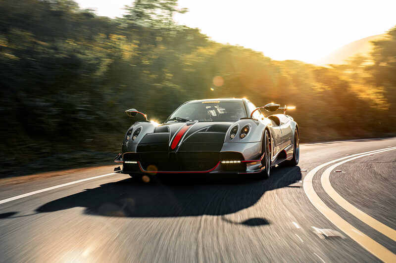 Pagani Huayra Roadster BC on a mountain road at golden hour, front three-quarter in motion