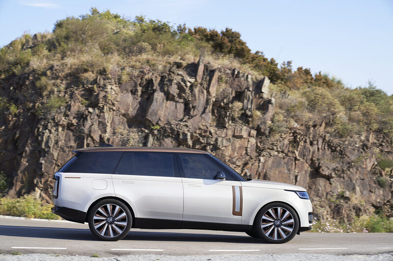 Range Rover SV in profile on a coastal road against a rock face